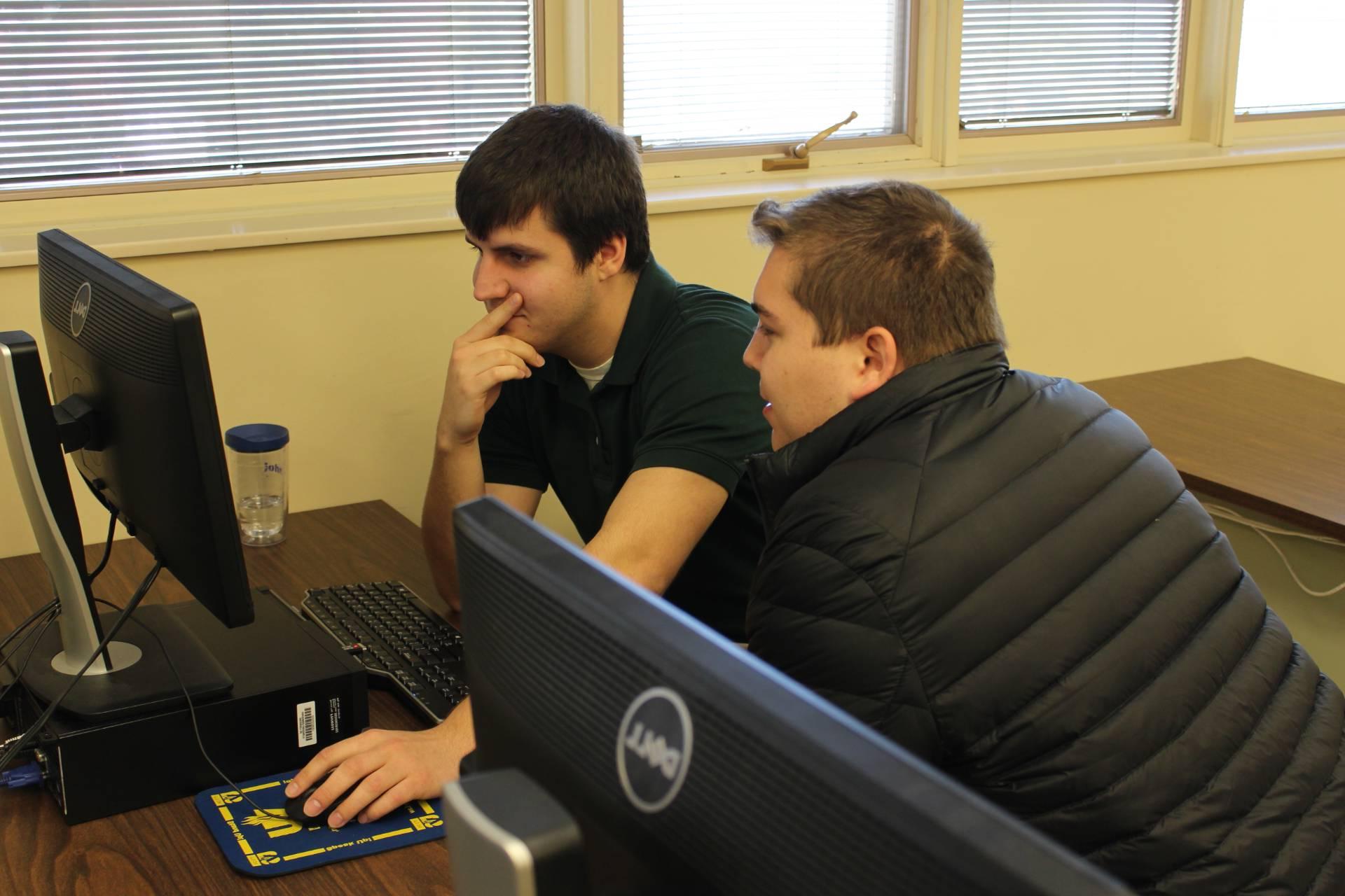 students at computer desk by wall